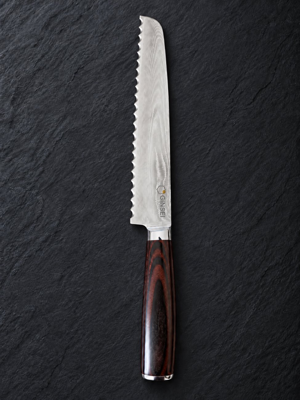 A pristine GINSEI Damascus bread knife with a crisp serrated edge